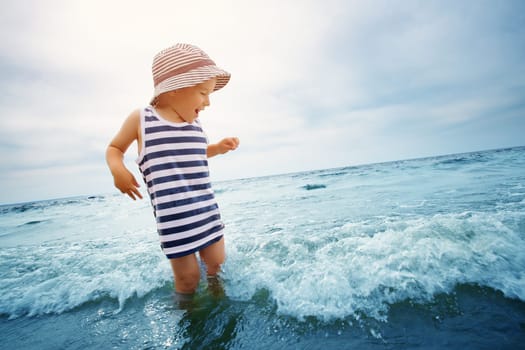three years old boy playing at the beach in the water. Happy child on family vacations at sea in summer. Summertime tourism and travel concept
