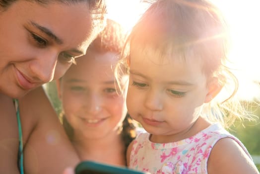 Girls looking at a phone outdoors at sunset
