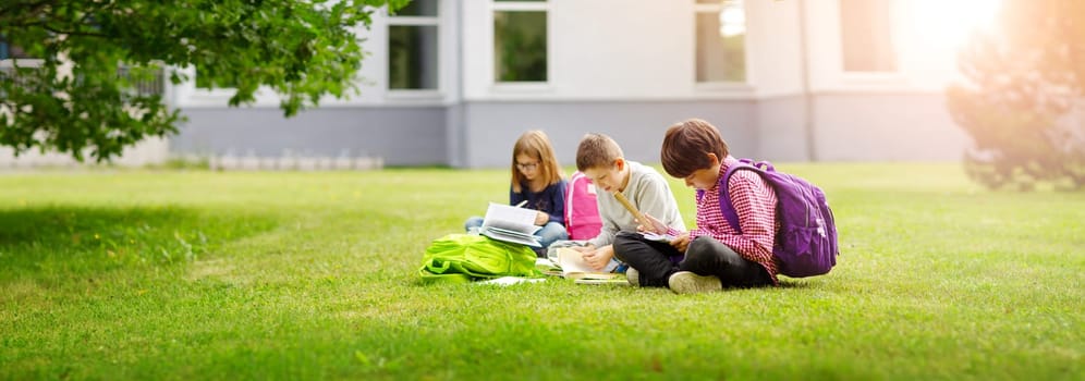 Children with rucksacks standing in the park near school. Pupils with books and backpacks outdoors