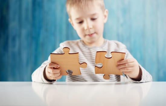 Little child holding puzzle pieces and trying to solve it. Problem solution concept