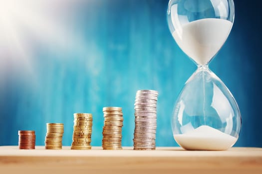 Clock with stacked coins. Pig with money savings and hourglass on blue background
