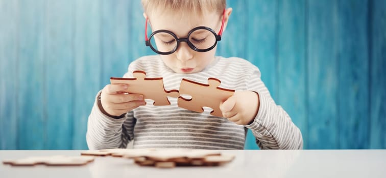 Little child holding puzzle pieces and trying to solve it. Problem solution concept