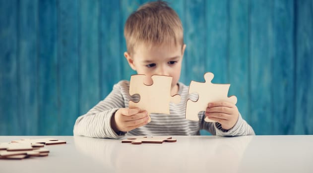 Little child holding puzzle pieces and trying to solve it. Problem solution concept