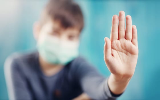 boy in medical face protection mask indoors on blue background. Sick child showing protest