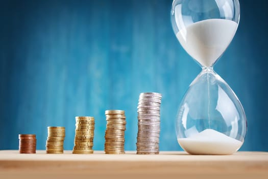 Clock with stacked coins. Pig with money savings and hourglass on blue background