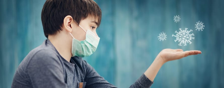 boy in medical face protection mask indoors on blue background. Sick child showing virus