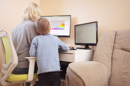 woman working at home with little child. Young businesswoman working indoors at pc