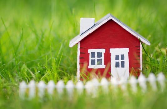 red wooden house model on the grass in garden