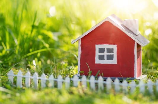 red wooden house model on the grass in garden