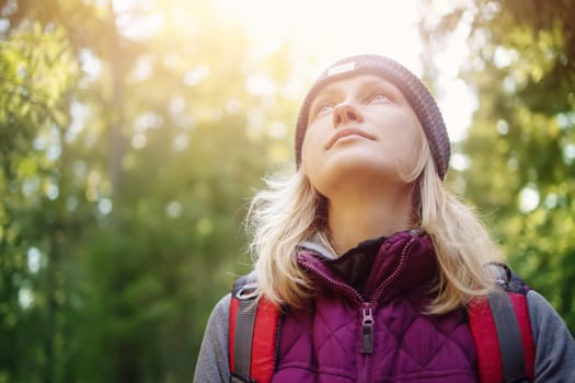 Young woman hiking and going camping in nature. Person with backpack walking in the forest