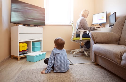 woman working at home with little child. Young businesswoman working indoors at pc