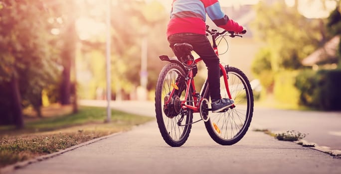 child on a bicycle at asphalt road in the evening