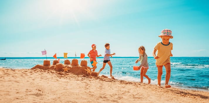 Boys and girl playing on the beach on summer holidays. Joyful children in nature with beautiful sea, sand and blue sky. Happy kids on vacations at seaside running in the water and having fun