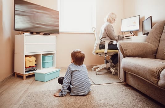 woman working at home with little child. Young businesswoman working indoors at pc