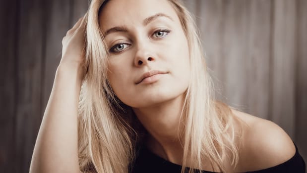 Happy beautiful young blond woman portrait with wooden background. Attractive girl in studio with long hair