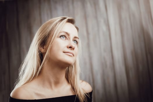 Happy beautiful young blond woman portrait with wooden background. Attractive girl in studio with long hair