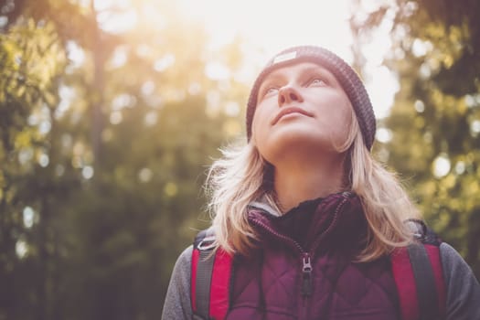 Young woman hiking and going camping in nature. Person with backpack walking in the forest