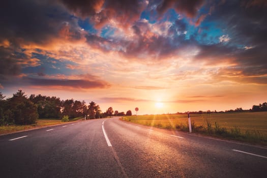black asphalt road and white dividing lines at sunset