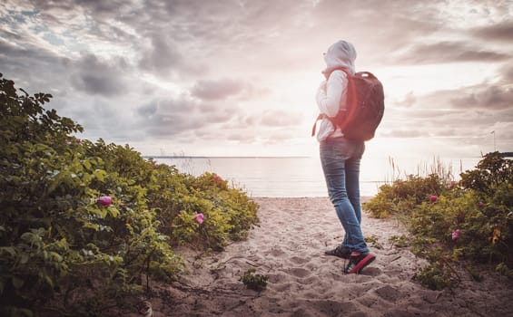 sea in sunset light. Woman in Lahemaa natural park coastal landscape with beautiful sky. Person with rucksack