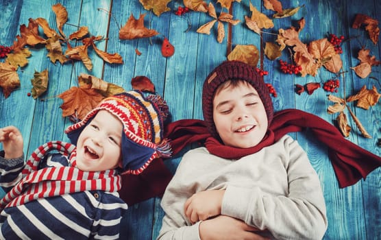 Boys dreaming in autumn. Children in hats and scarfs and maple leaves on blue background