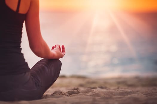 young woman sitting on the beach and practicing yoga