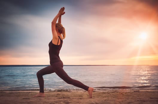 young woman sitting on the beach and practicing yoga