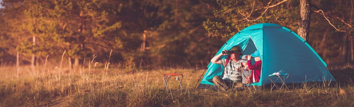 Family resting with tent in nature at sunset. man and child near seaside