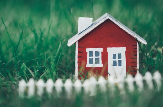 red wooden house model on the grass in garden