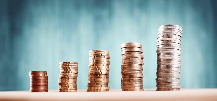 stacked coins on blue background. Money columns with different heigth