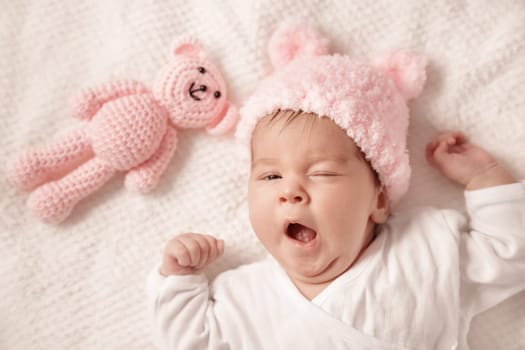 Cute newborn baby girl lying in the bed. Two month old infant child on white soft blanket with teddy bear