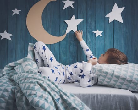 Five years old child sleeping in bed. Boy lying with closed eyes at night