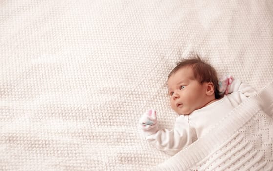 Cute newborn baby girl lying in the bed. Two weeks old infant child on white soft blanket