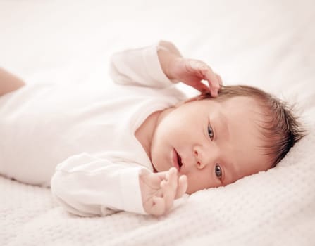 Cute newborn baby girl lying in the bed. Two weeks old infant child on white soft blanket