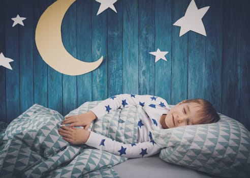 Five years old child sleeping in bed. Boy lying with closed eyes at night
