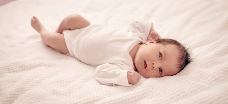 Cute newborn baby girl lying in the bed. Two weeks old infant child on white soft blanket
