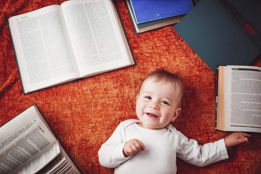One year old baby among books with spectackles.Happy little child reading