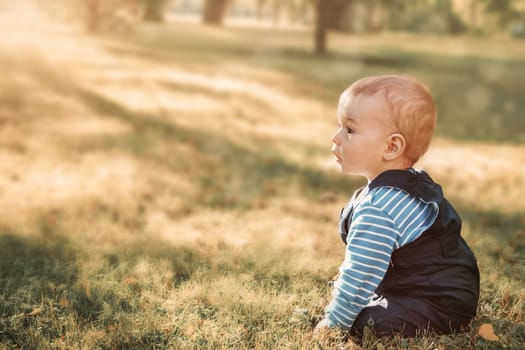 little nine month old baby sitting in the park in beautiful evening