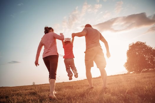 girl with mother and father holding hands on the nature. Child with parents outdoors
