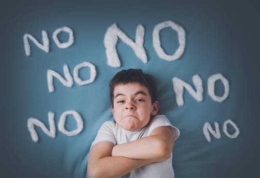 bad boy on blue blanket background. Angry child with no words around