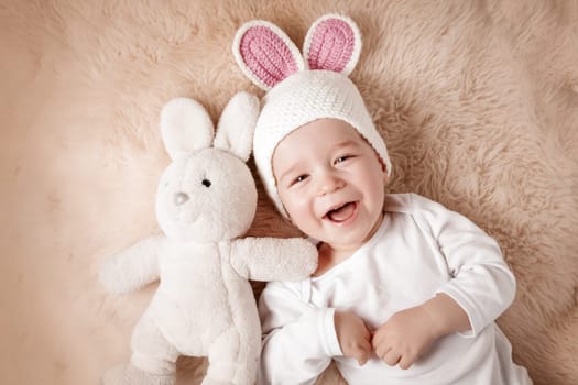sleepy one year old baby lying in bunny hat on lamb wool background