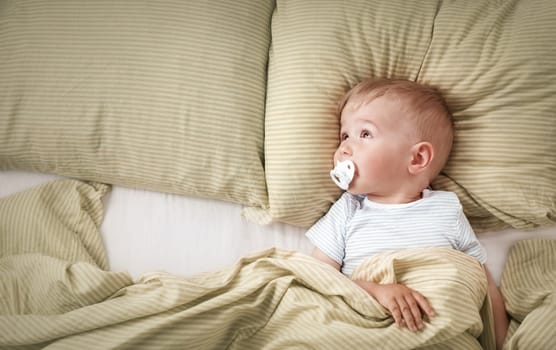 One year old baby lying in the bed with green bedding