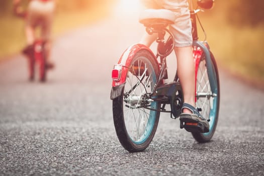 children on a bicycle at asphalt road in early morning