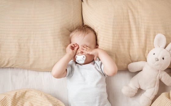 One year old baby lying in the bed with green bedding
