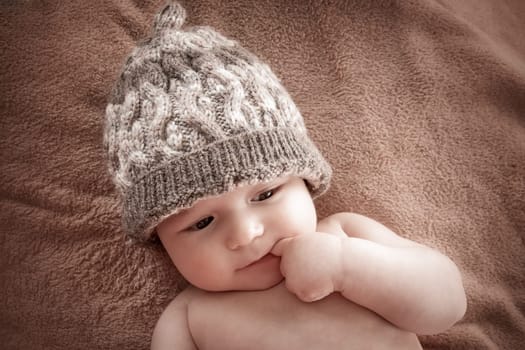 cute baby in hat on brown fur background