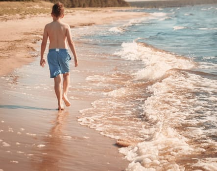 boy barefoot is jumping on the beach in water. Child is on vacation in summer at the sea
