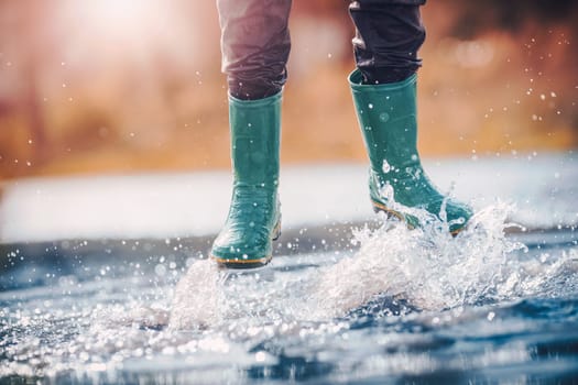 Child walking in wellies in puddle on rainy weather. Boy under rain in summer