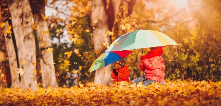 children with umbrellas in beautiful autumnal day. Boys playing outdoors in the park