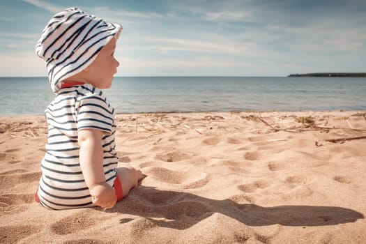 Nine month old baby boy sitting on the beach in beautiful summer day
