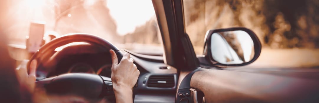 Driver driving a car on asphalt road in summer day at park. Woman at steering wheel