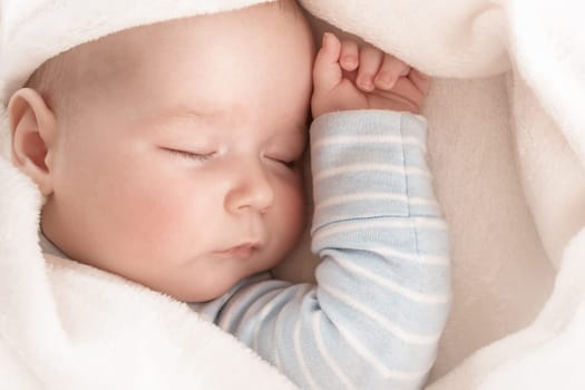 little boy sleeping on soft white blanket